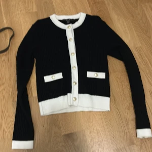 Jätte fin kofta💖 - Snygg svart kofta från Amisu med vita detaljer och guldknappar i storlek s. Den har långa ärmar och en klassisk rund halsringning. Perfekt för en stilren look. Aldrig använd💕💕priset går att diskutera