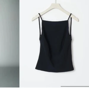 Svart Gina topp - Snygg svart axelbandslös topp med smala axelband. Perfekt för en stilren look. Passar bra till både jeans och kjol.