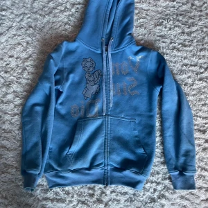 Blå rhinestone hoodie från Vonstudio - Säljer en blå hoodie från Vonstudio i strlk XS. Fästet på dragkedjan är trasigt men det går ändå att dra upp den.