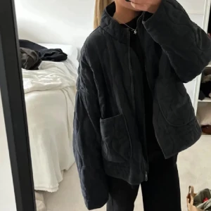 Svart quiltad jacka - Säljer en svart jacka med dragkedja och stora fickor framtill ifrån Zara. Jackan har en oversized passform och långa ärmar. Som på andra bilden är den lite nipprig, men går lätt att ta bort med noppermaskin.