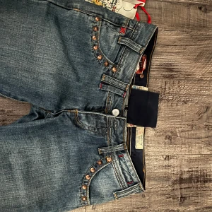 Lågmidjade jeans - Snygga blå jeans med nitar vid fickorna och broderade detaljer på bakfickorna. Säljer då de är för små, därav inga bilder på. Storlek 26x34, mått: midja 34cm innerben 84~85cm hela jeansen 104cm. Om ni har frågor tveka inte att ställa dem<3