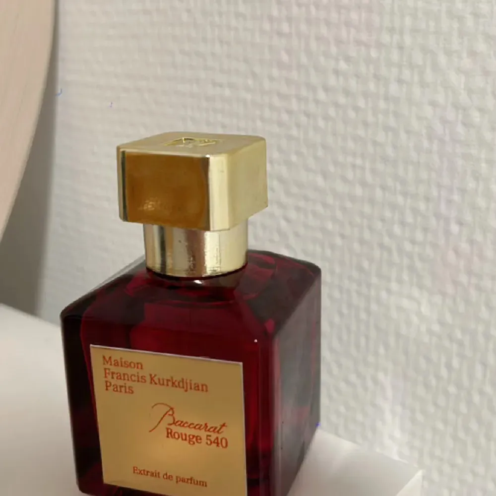 Säljer en lyxig parfymflaska av Maison Francis Kurkdjian, Baccarat Rouge 540 Extrait de Parfum. Flaskan är elegant och djup röd med en gyllene etikett och kork. Perfekt för den som vill ha en exklusiv doftupplevelse. Passar både till vardags och speciella tillfällen.. Parfym.