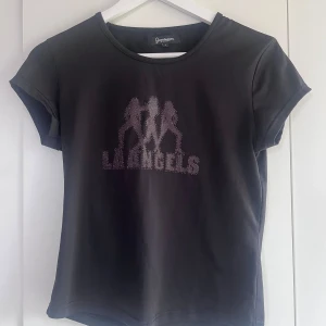 T-shirt  - Svart T-shirt med tryck köpt på secondhand är i storlek L, passar även s-m beroende på hur tajt man vill den ska sitta, aldrig använd av mig 