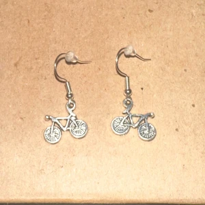 Cykelörhängen i silver - Säljer ett par unika örhängen i form av cyklar. De är i silverfärg och har en cool design som passar perfekt för cykelentusiaster. Örhängena är lätta och bekväma att bära hela dagen. Perfekta för att ge en personlig touch till din outfit!