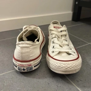 Beige Converse All Star sneakers - Säljer ett par klassiska beige Converse All Star sneakers i storlek 37. De är välanvända men fortfarande i bra skick. Perfekta för en avslappnad stil och funkar året runt. Skorna har snörning och den ikoniska gummisulan med röd och blå rand.