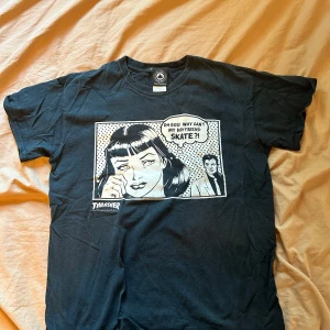 Svart Thrasher t-shirt med serietryck - Säljer en svart Thrasher t-shirt i storlek M. Den har ett nice tryck på framsidan med texten 'Oh God! Why can't my boyfriend skate?!'. Perfekt vardagströja. T-shirten är i bomull och har en normal passform. Något slitet tryck