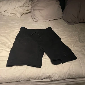 Svarta Hugo shorts - Säljer ett par svarta shorts i storlek XS. De är perfekta för en avslappnad dag eller träning. Shortsen har en enkel design med snörning i midjan för justerbar passform. Materialet känns mjukt och bekvämt. Hugo shorts köpta på paparazzi Malmö.