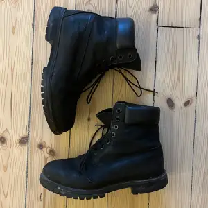 Säljer ett par svarta kängor från Timberland i använt skick. De har en robust sula och klassisk snörning, perfekt för höst och vinter. Perfekta för att hålla fötterna varma och torra under kalla dagar. Lite slitna i hälen på insidan, därav billiga. Går bra att putsa upp dom!