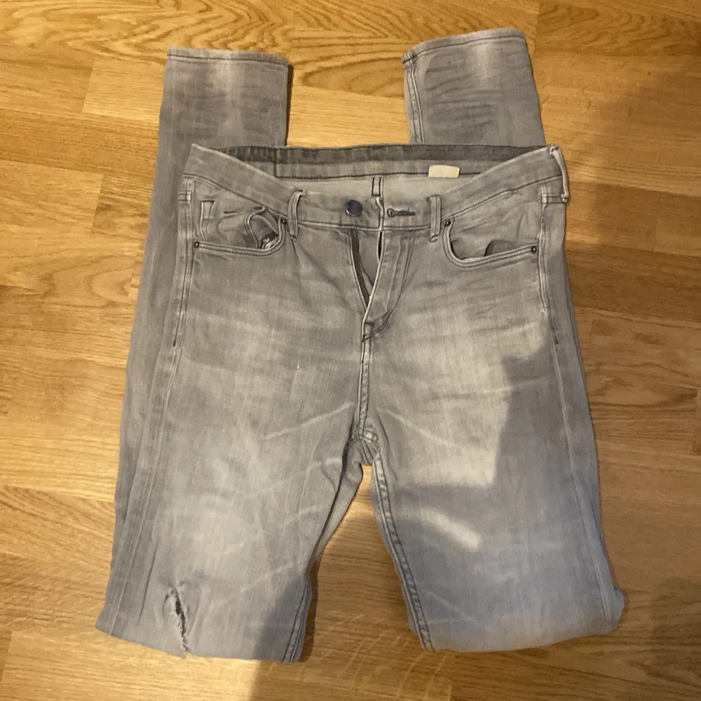 Säljer ett par grå skinny jeans i storlek 28x34. De har en snygg slitning på ena knät och är perfekta för en casual look. Jeansen är i bra skick och passar till både vardag och fest. Sköna och stretchiga för bästa komfort!. Jeans & Byxor.