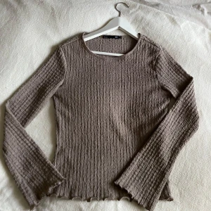 Beige ribbad tröja - Säljer en superfin beige ribbad tröja med långa ärmar och volangdetaljer vid ärmslut och nederkant. Perfekt för höst och vår, den är både stilren och bekväm. Passar till både vardag och fest! 💞