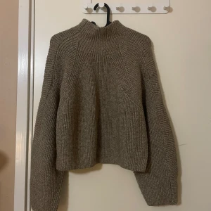 Stickad tröja - Mysig beige/brun stickad tröja från H&M i storlek S. Perfekt för kyliga dagar med sin varma och bekväma design. Tröjan har långa ärmar och en hög krage som håller dig varm.