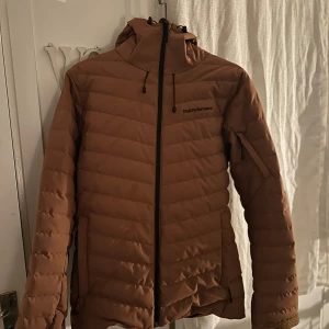 Brun pufferjacka från Peak Performance - Säljer en brun pufferjacka från Peak Performance i storlek M. Jackan har en dragkedja framtill och är långärmad. Perfekt för höst och vinter med sin varma och stilrena design. Den är i bra skick och redo för nya äventyr!