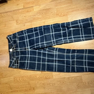 Rutig jeansbyxa från monki - Säljer ett par snygga blå jeans med vitt/ljusblått rutmönster. Supersnygga byxor jag har älskat men de har blivit för små för mig o därför jag säljer vidare. Byxorna har en klassisk femficksdesign och knappar i silverfärg. Perfekta för en avslappnad