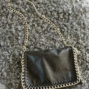 Axelremsväska  - Säljer en svart axelremsväska i skinn då den inte kommer till användning längre, den är i bra skick och använd ett fåtal gånger