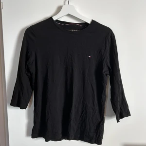 Svart långärmad tröja från Tommy Hilfiger - Säljer en stilren svart långärmad tröja från Tommy Hilfiger. Tröjan har en liten logga på bröstet och är perfekt för både vardag och lite finare tillfällen. Den är i bra skick och superbekväm att ha på sig. Passar perfekt till jeans eller chinos!