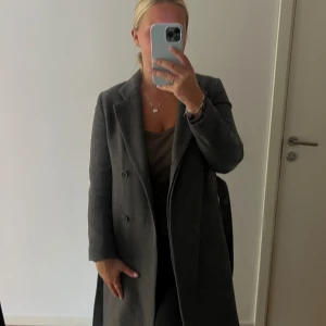 Filippa K kappa - Den perfekta kappan från Filippa K. I en underbar mörkgrå färg och med både knytning och knäppning.  Säljs då den inte passar längre 😔