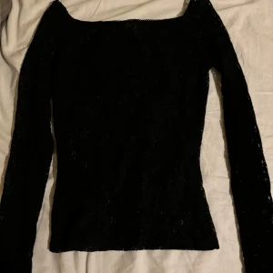 Svart långärmad topp från Aware - Säljer en elegant svart långärmad topp från veromoda. Den har en mönstrad genomskinlig design som ger en cool look. Perfekt för både vardag och fest