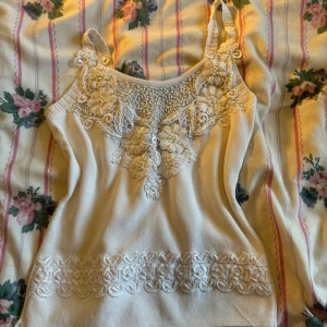 Vit linne med spetsdetaljer - Säljer en superfin vit linne med vackra spetsdetaljer och blommönster på framsidan. Den har smala axelband och är perfekt för sommaren. Materialet känns mjukt och bekvämt. finns en defekt på sista bilden men jag tror att den går bort i tvätten. själva linnet är vinstge och var min mammas i 2000 talet pris kan diskuteras💗💗🎀pris kan alltid diskuteras🎀