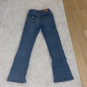 Bootcut jeans - As snygga bootcut jeans från Gina, med knappar på fickorna! De är använda men inget som syns. De är justerbara i midjan. Säljer då jag växt ur dem! Minns inte hur mycket de kosta, därav säljer jag dem för bara 150kr!