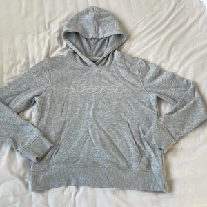 GANT hoodie  - Grå GANT hoodie i storlek 170 med glittrig text och en ficka fram. Nyskick, är inte alls nopprig. Sparsamt andvänd. 