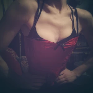 Röd korsett med svarta detaljer - Snygg röd korsett med svarta band och en liten rosett framtill. Perfekt för en festlig kväll eller en speciell tillställning. Den har en tight passform som framhäver figuren och ger en elegant look.