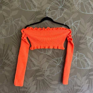 Orange ribbad offshoulder topp från Madlady - Säljer en superfin orange ribbad offshoulder topp från Madlady. Den är croppad och har långa ärmar med volangdetaljer vid kanterna. Perfekt för en utekväll eller fest! 🧡