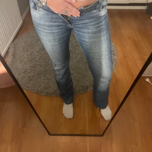 Blå jeans i bootcut-stil - Säljer ett par snygga blå jeans i bootcut-stil. De är i bra skick och har en klassisk femficksdesign med knapp och dragkedja framtill. Perfekta för både vardag och fest! Passar till allt från sneakers till klackar. Från lee, uppsprättad då de är korta på mig, är ca 170cm💙