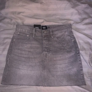 Grå jeanskjol från 157 - Säljer en snygg grå jeanskjol från 157 i storlek S. Kjolen har en klassisk femficksdesign och en rå kant nertill för en trendig look. Perfekt för både vardag och fest! 🖤