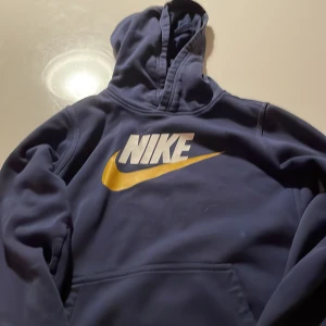En Nike tröja som är mörkblå med två små hål i ryggen - Den är fin men det är tyvärr två små hål i ryggen. Pris kan diskuteras.