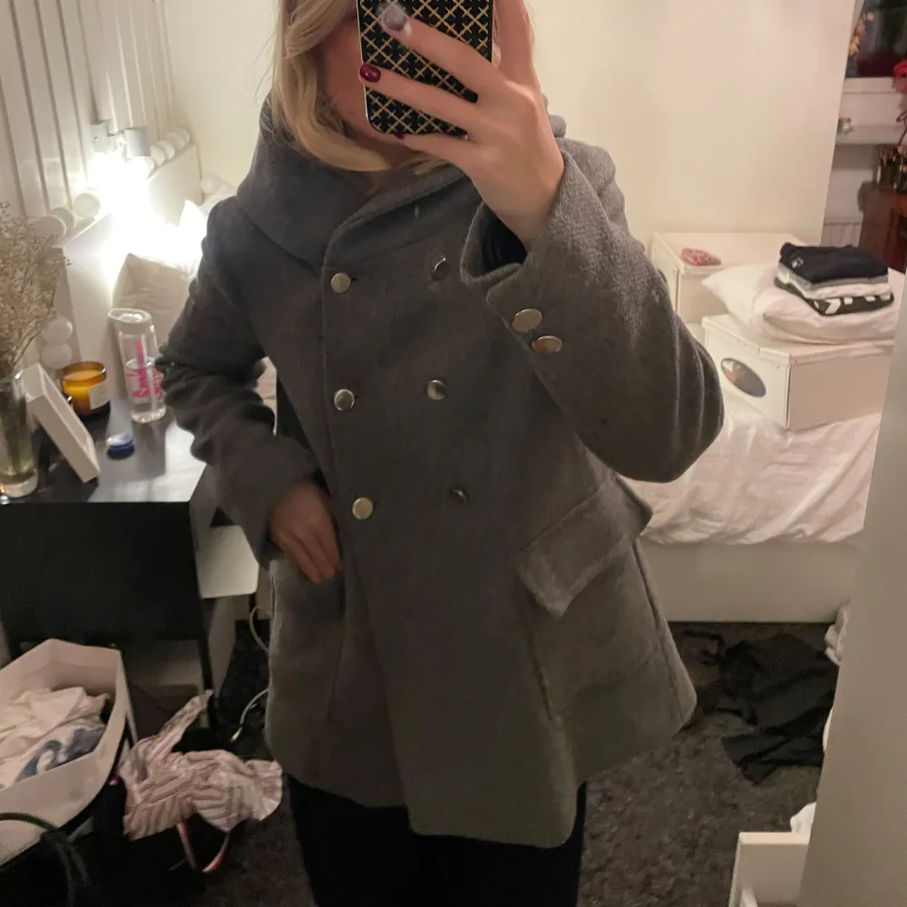 Snygg grå kappa från Zara med dubbelknäppning och stora fickor. Den har en luva och långa ärmar. Storlek M . Takit.