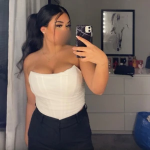 Vit axelbandslös tubtopp/ korsett - Snygg vit axelbandslös tubtopp/korsett som passar perfekt till både jeans och kjol. Toppen är tight och framhäver figuren på ett stilrent sätt. Perfekt för varma sommardagar eller en utekväll.🤗