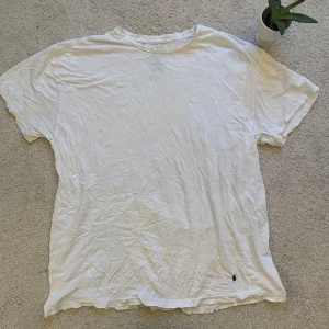 Vit t-shirt från Ralph Lauren - Säljer en klassisk vit t-shirt från Ralph Lauren i bomull. Den har en liten broderad logga i nederkant och korta ärmar. Perfekt för en avslappnad stil.