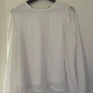 Vit blus  - En vit oanvänd blus med fina detaljer både i nacken och i ärmarna med fina knappar. I storlek M men passar även de som har S.