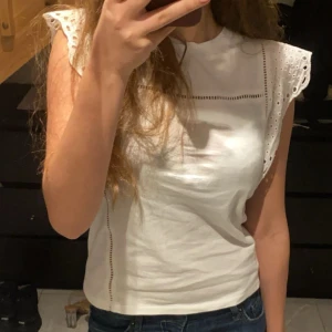 Vit ärmlös topp med spetsdetaljer - Säljer en söt vit topp med spetsdetaljer på axlarna. Toppen är ärmlös och har en fin, luftig design som passar perfekt för varmare dagar. Perfekt att matcha med jeans eller kjol för en avslappnad look. Jätte fin älskar den men kommer tyvärr inte till använder knappt använd!! Skriv om frågor! Storlek xs men passar xs oxh s. Pris kan diskuteras