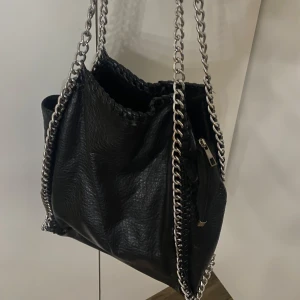 Väska från tiamo  - Snygg svart axelväska i syntetmaterial med coola kedjedetaljer. Lite slitningar men annars i fint skick💗💗