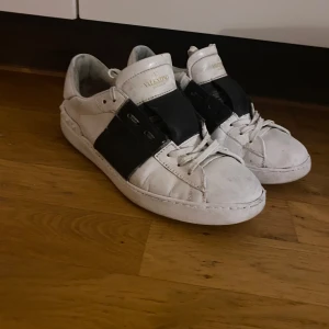 Valentino Open  - Säljer ett par vita sneakers från Valentino Garavni i bra skick. De har en cool svart detalj på sidan och klassisk snörning. Perfekta för både vardag och fest! Skorna är lite smutsiga men kan enkelt rengöras för att se fräscha ut igen. Skorna är äkta bara till att fråga har fått äkthetsbevis av många företag men ställ era frågor Mvh! 