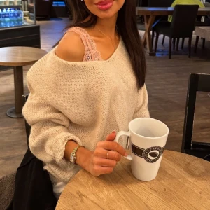 Beige stickad tröja - Mysig beige stickad tröja med en avslappnad passform. Tröjan har en offshoulder-design och långa ärmar, perfekt för en bekväm och stilren look. Passar utmärkt för kyligare dagar.