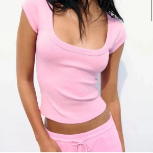 Rosa topp från zara - Säljer en söt rosa ribbad topp från Zara. Den har en tight passform och korta ärmar, perfekt för sommardagar. Toppen är gjord i ett mjukt och stretchigt material som sitter skönt mot kroppen.