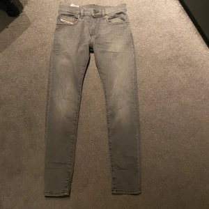Grå jeansbyxor från Diesel - Snygga grå jeansbyxor från Diesel med en klassisk femficksdesign. Byxorna har en straight passform och är perfekta för en avslappnad stil. De har en knappgylf och en liten Diesel-logga på fickan.slim jeans