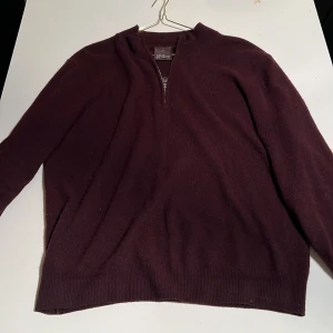 Vinröd tröja från Oscar Jacobson  - Säljer en stilren vinröd  tröja från Oscar Jacobson med dragkedja vid halsen. Tröjan har långa ärmar och är perfekt för kyligare dagar. Passar bra till både jeans och chinos.