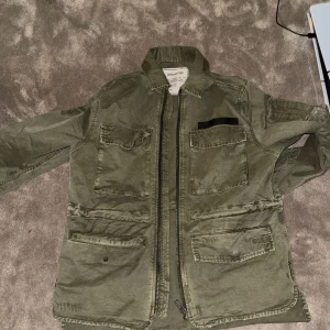 Grön jacka från Zadig & Voltaire - Säljer en grön jacka från Zadig & Voltaire med dragkedja och flera praktiska fickor. Jackan har en vintage-inspirerad stil och är perfekt för en avslappnad look.