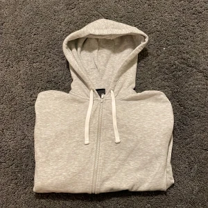 Grå zip hoodie i suveränt skick - Säljer en grå zip hoodie i suveränt skick, tröjan är näst intill oanvänd och den har samma mjuka känsla som när jag köpte den.