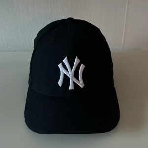 Marinblå 59fifty keps från New Era - Snygg marinblå keps från New Era med broderad vit logga framtill. Kepsen är en del av Cooperstown Collection och har en broderad detalj på sidan. 