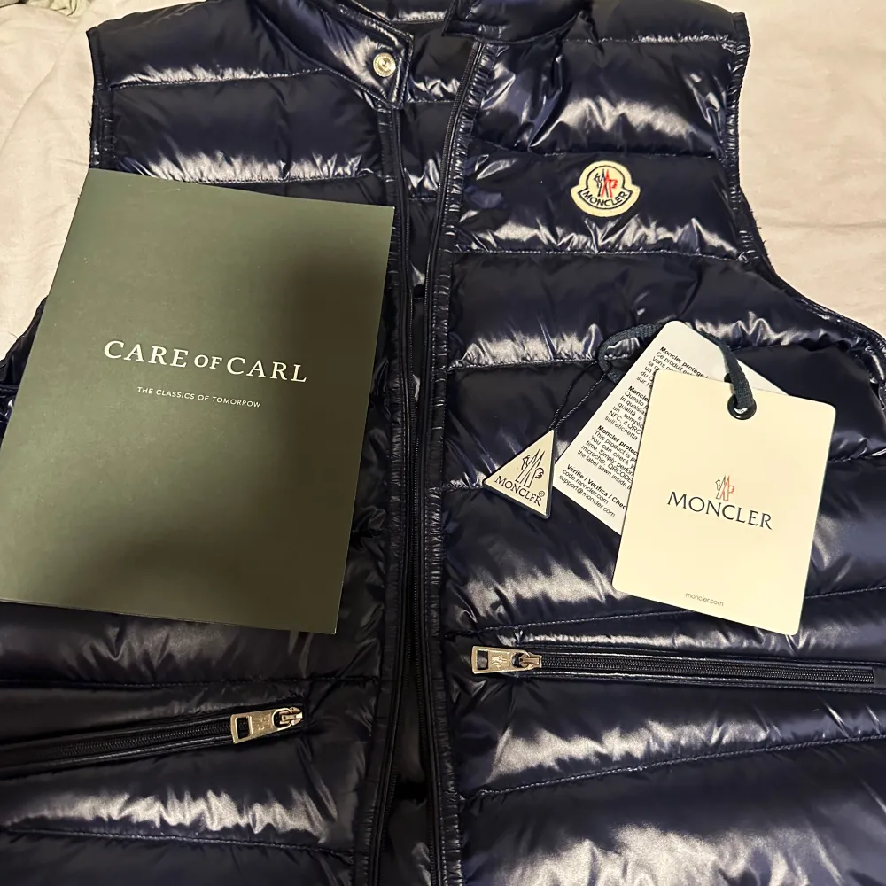 Säljer en snygg blå dunväst från Moncler med glansig finish. Västen har dragkedja och två praktiska fickor med dragkedjor framtill. Perfekt för att hålla värmen med stil. Lite seg när man drar upp dragkedjan men annars inga defekter! Säljer för den blivit för liten. Pris kan diskuteras! Storlek 1. Takit.