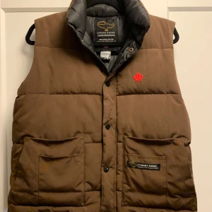 Canada Goose väst  - Säljer den dunder västen från Canada Goose! skick 8/10 tecken på användning vid noga inspektion | OBS! Zippern på dragkedjan har tyvärr gått sönder, men det borde inte vara något problem med att få det lagat hos t.ex. en skräddare | Passar: 155-170 | Nypris: 7000 kr | Tveka inte att höra av er vid frågor och funderingar! Kan sänka pris vid snabb affär! Mvh Finn’s Resell