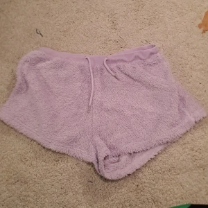 Lila fluffiga shorts - Mysiga lila shorts i fluffigt material med snörning i midjan. Perfekta för en avslappnad dag hemma eller som ett bekvämt lager under kyligare dagar.