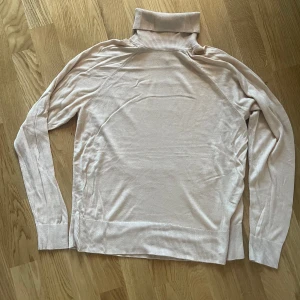 Beige polotröja från H&M - Säljer en stilren beige polotröja från H&M Basics. Tröjan har långa ärmar och en klassisk polokrage, perfekt för kyligare dagar. Den är tillverkad i ett mjukt material som ger en bekväm passform.