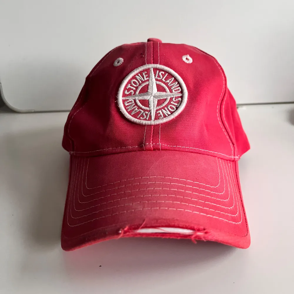 Snygg handfärgad röd keps från Stone Island med broderad logga framtill. Kepsen har en klassisk design med justerbart spänne baktill för perfekt passform. Perfekt för en avslappnad stil.. Asusteet.