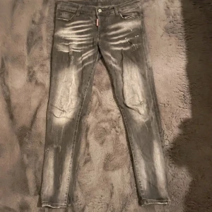 Grå jeans från Dsquared2 - Snygga grå jeans från Dsquared2 med en cool tvättad look och slitna detaljer. De har en knappgylf och en unik etikett på baksidan. Perfekta för en trendig stil. Hål på högra sidan byxan med enklat att fixa. Slimfit storlek 48. Kom PM för snabbaffär 