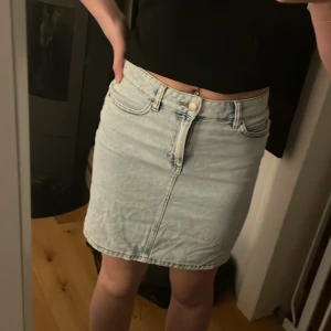 Ljusblå jeanskjol - Snygg ljusblå jeanskjol med klassisk femficksdesign och knappgylf. Perfekt för en avslappnad stil. Kjolen har en kort längd och en normal passform.🩵🩵Superfint skick! Hör av dig vid intresse🥰